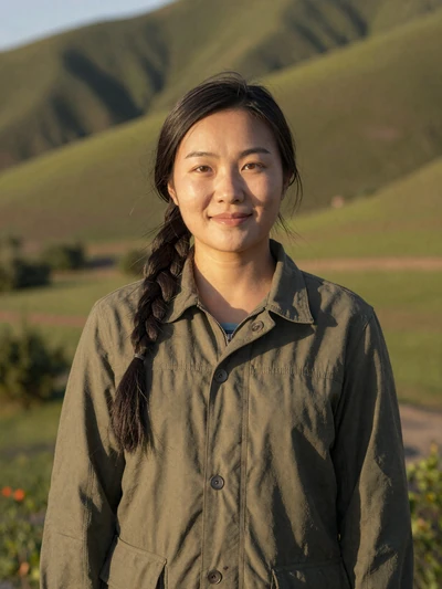 Solongo, 29, Mongolian woman in olive jacket with steppe hills behind her - Mongolian dating profile